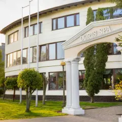 Elegancki budynek Doris Spa w Kołobrzegu z kolumnowym wejściem i kwitnącymi drzewami.