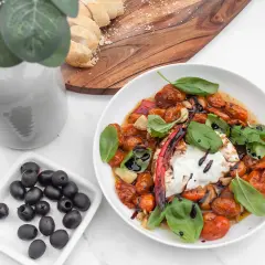 Pyszny burrata przepis: kremowy ser z pieczonymi pomidorkami, czosnkiem, bazylią i oliwkami. Idealny na letni obiad.