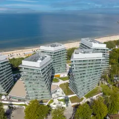 Nowoczesny wave resort z tarasami i widokiem na morze. Architektura idealnie wkomponowana w nadmorski krajobraz.