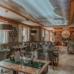 Przytulna restauracja w górach z widokiem na las. Drewniane belki, kamienne detale i sufit z malowniczym krajobrazem tworzą niepowtarzalny klimat.