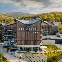 Nowoczesny hotel Elements w Świeradowie-Zdroju, otoczony zielenią, z widokiem na góry.