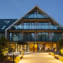Nowoczesny budynek Saltic Resort & Spa Łeba z betonowymi elementami i przeszklonymi balkonami, oświetlony wieczorem.