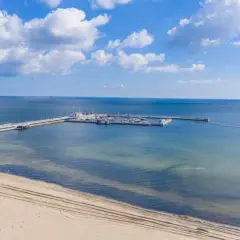 Molo z jachtami i żaglówkami, plaża i koparka – idealne atrakcje nad morzem dla każdego.