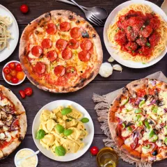 Uczta w stylu kuchnia włoska: pizze, spaghetti z klopsikami, fettuccine i tortellini na drewnianym stole.