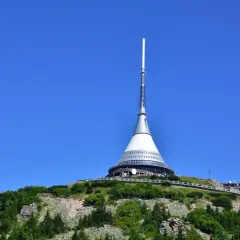 Wieża telewizyjna Ještěd, jedna z głównych libereckich atrakcji, góruje nad zielonym wzgórzem.