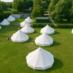 Wioska glampingowa nad morzem. Białe namioty tipi na zielonej trawie, otoczone drzewami.