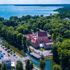 Malowniczy hotel na Mazurach, otoczony zielenią i wodą, z widokiem na jezioro. Idealne miejsce na wypoczynek.