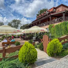 Letnie popołudnie w jednej z najlepszych restauracji na Mazurach. Goście odpoczywają pod parasolami, ciesząc się widokiem na jezioro.