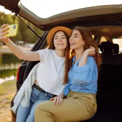 Dwie przyjaciółki robią sobie selfie nad jeziorem, ciesząc się wspólnym weekendem.