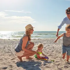 Rodzina bawi się na plaży z dziećmi, budując zamki z piasku.