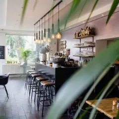 Wnętrze restauracji z barem, stołkami i stołami.
