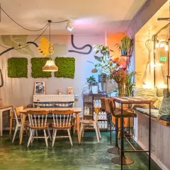 Wnętrze pełne zieleni i sztuki, tworzące przytulną atmosferę. Idealne miejsce na relaks w jednej z klimatycznych restauracji w Poznaniu.