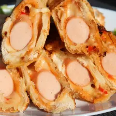 Pyszne domowe hot dogi w cieście, zapieczone z serem i papryką. Idealne na szybką przekąskę.