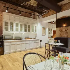 Eleganckie wnętrze restauracji Arche Klasztor Wrocław. Drewniana podłoga, ceglane ściany i białe meble tworzą przytulną atmosferę.