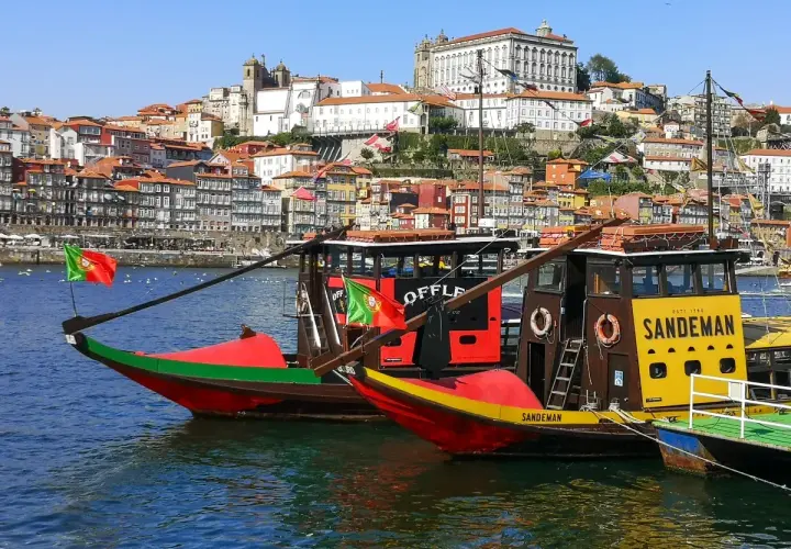 Porto na weekend: tradycyjne łodzie Rabelo na rzece Douro, z kolorowymi domami i zabytkowymi budynkami w tle.