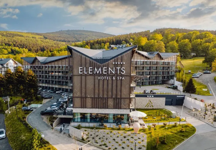 Nowoczesny hotel Elements w Świeradowie-Zdroju, otoczony zielenią, z widokiem na góry.