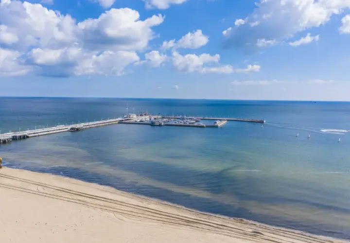 Molo z jachtami i żaglówkami, plaża i koparka – idealne atrakcje nad morzem dla każdego.