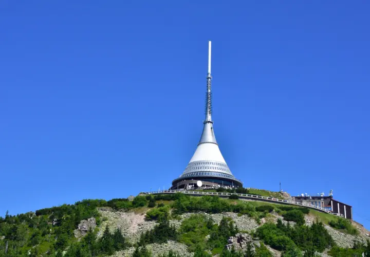 Wieża telewizyjna Ještěd, jedna z głównych libereckich atrakcji, góruje nad zielonym wzgórzem.