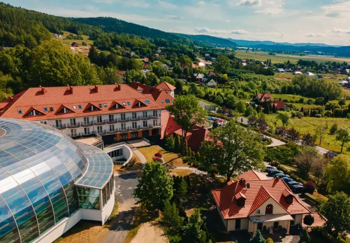 Kyriad Karkonosze: hotel z kopułą i basenem, otoczony zielenią i górami.