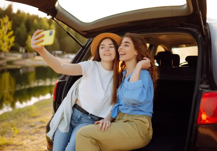 Dwie przyjaciółki robią sobie selfie nad jeziorem, ciesząc się wspólnym weekendem.