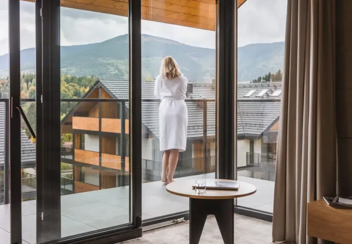 Kobieta w szlafroku podziwia widok na góry z tarasu hotelu Tremonti Karpacz.