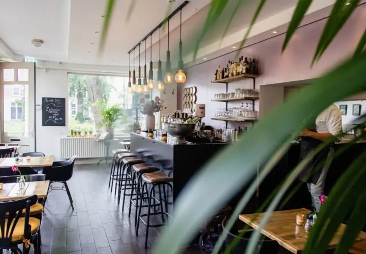Wnętrze restauracji z barem, stołkami i stołami.