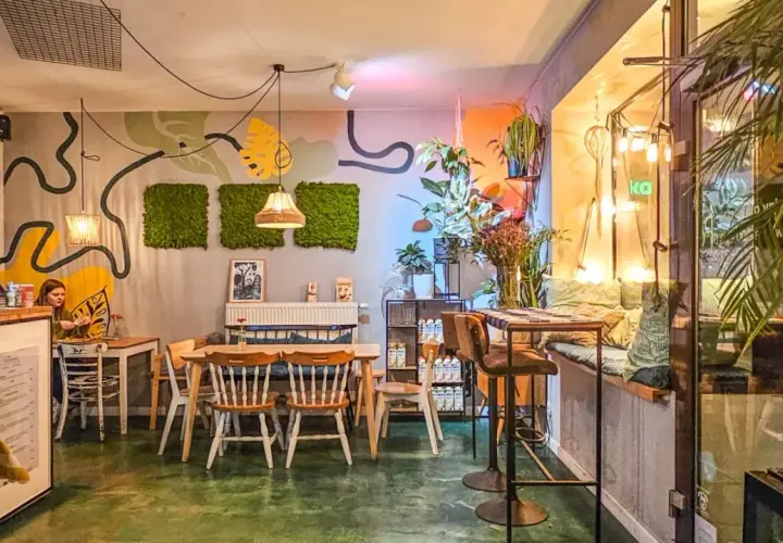 Wnętrze pełne zieleni i sztuki, tworzące przytulną atmosferę. Idealne miejsce na relaks w jednej z klimatycznych restauracji w Poznaniu.