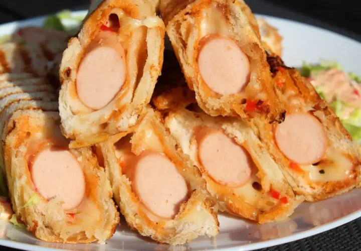 Pyszne domowe hot dogi w cieście, zapieczone z serem i papryką. Idealne na szybką przekąskę.