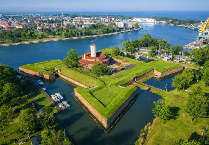 Twierdza Wisłoujście w Gdańsku – ciekawe miejsce do zwiedzenia, otoczone fosą i zielenią, z widokiem na port.