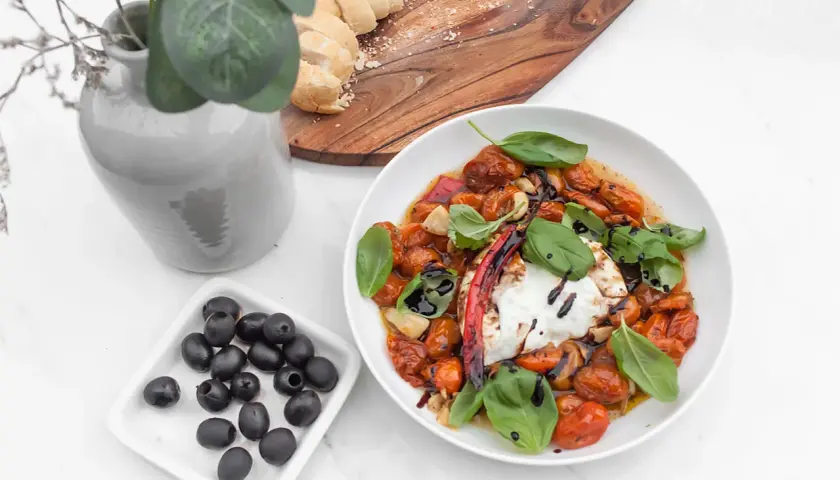 Pyszny burrata przepis: kremowy ser z pieczonymi pomidorkami, czosnkiem, bazylią i oliwkami. Idealny na letni obiad.