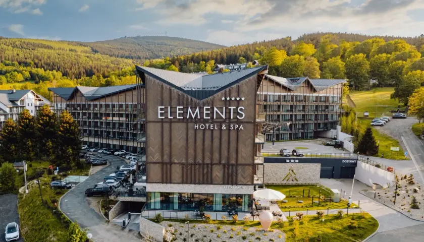 Nowoczesny hotel Elements w Świeradowie-Zdroju, otoczony zielenią, z widokiem na góry.