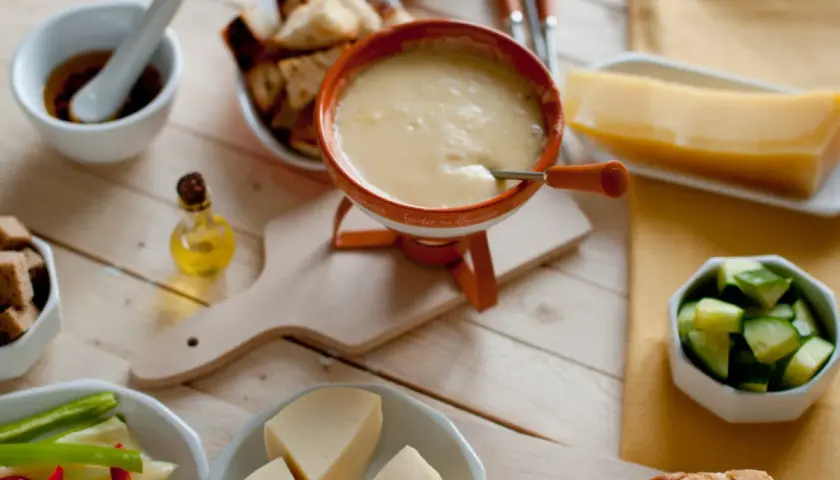 Pyszne fondue serowe z dodatkami: pieczywo, warzywa i kawałek sera. Idealny wybór, jaki ser do fondue?