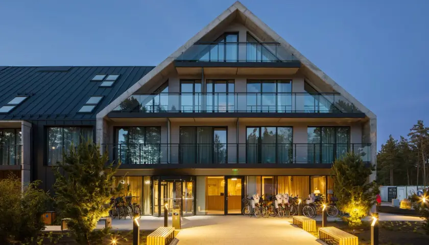 Nowoczesny budynek Saltic Resort & Spa Łeba z betonowymi elementami i przeszklonymi balkonami, oświetlony wieczorem.