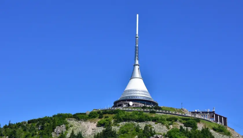 Wieża telewizyjna Ještěd, jedna z głównych libereckich atrakcji, góruje nad zielonym wzgórzem.