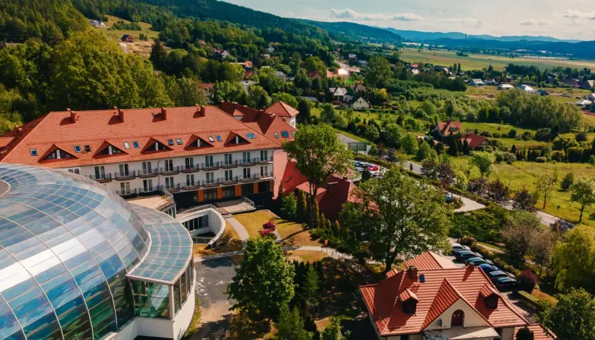 Kyriad Karkonosze: hotel z kopułą i basenem, otoczony zielenią i górami.