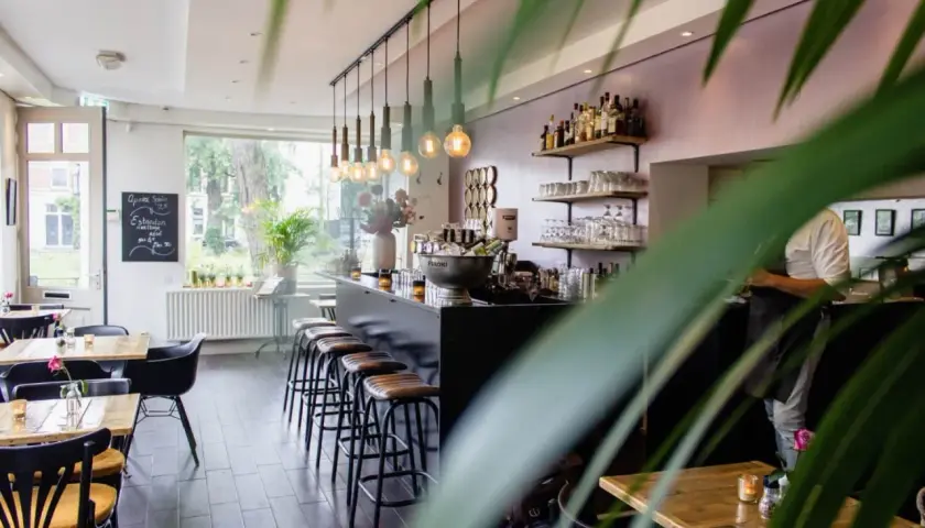 Wnętrze restauracji z barem, stołkami i stołami.