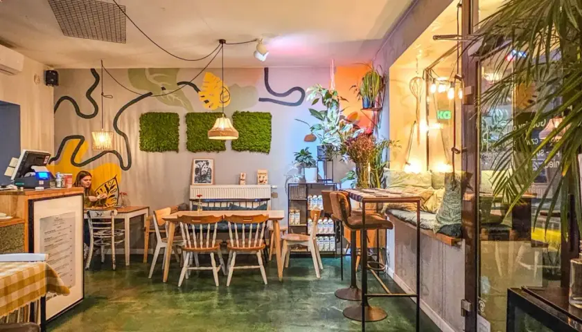 Wnętrze pełne zieleni i sztuki, tworzące przytulną atmosferę. Idealne miejsce na relaks w jednej z klimatycznych restauracji w Poznaniu.