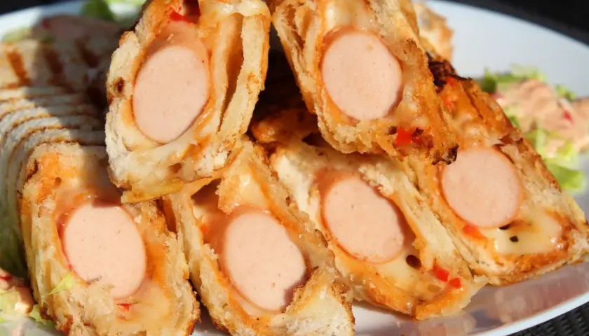 Pyszne domowe hot dogi w cieście, zapieczone z serem i papryką. Idealne na szybką przekąskę.