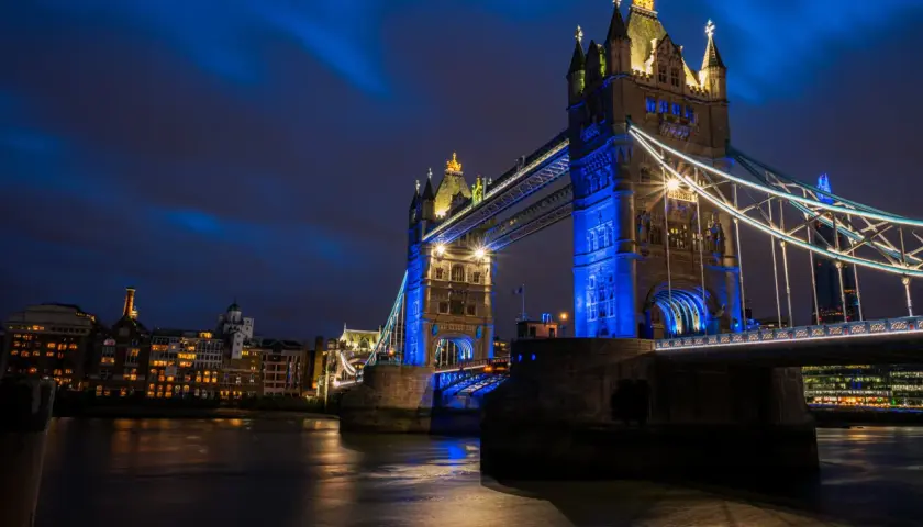 Tower Bridge w Londynie, jedna z głównych wielka brytania atrakcje, nocą, oświetlona na niebiesko.