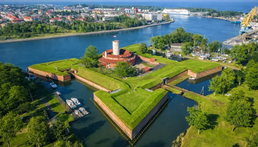 Twierdza Wisłoujście w Gdańsku – ciekawe miejsce do zwiedzenia, otoczone fosą i zielenią, z widokiem na port.