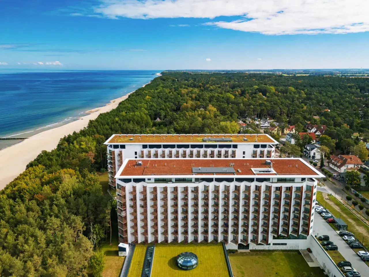 Pinea Resort Pobierowo, nowoczesne budynki hotelowe z widokiem na morze i las.