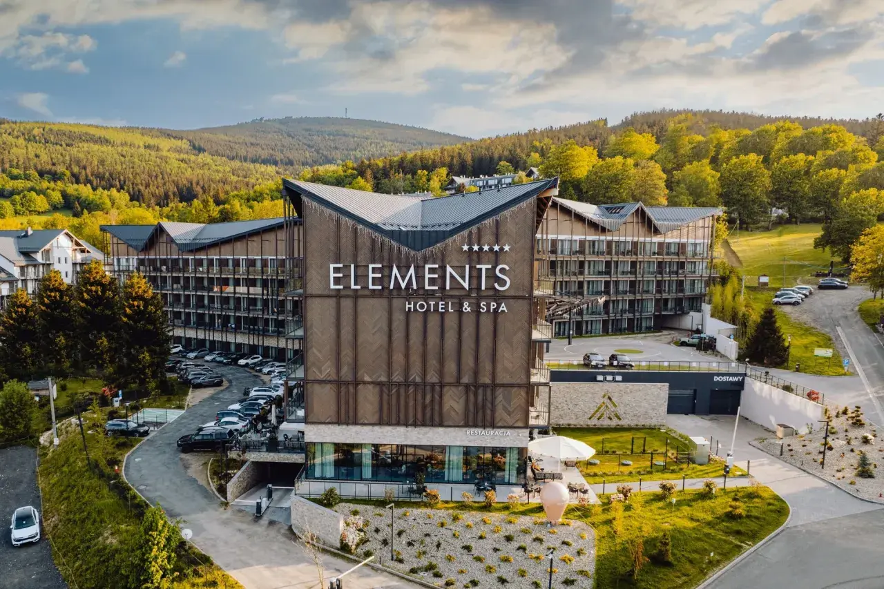 Nowoczesny hotel Elements w Świeradowie-Zdroju, otoczony zielenią, z widokiem na góry.