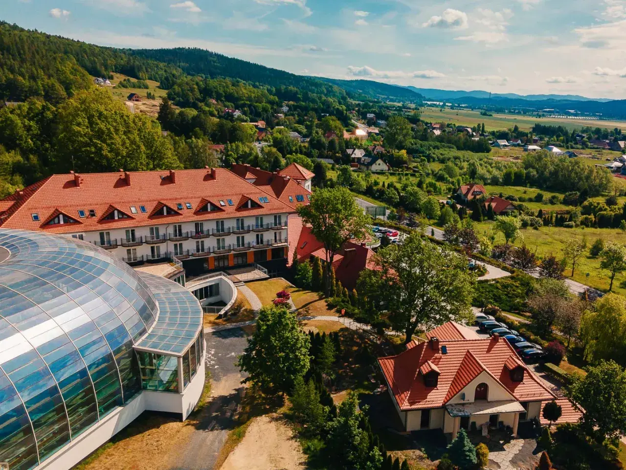 Kyriad Karkonosze: hotel z kopułą i basenem, otoczony zielenią i górami.