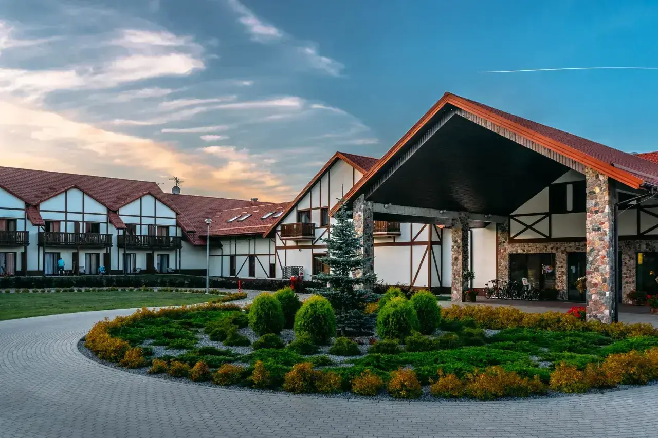 Hotel Mikołajki Leisure & Spa zaprasza do wypoczynku. Piękny budynek z kamiennymi elementami i zadbanym ogrodem.