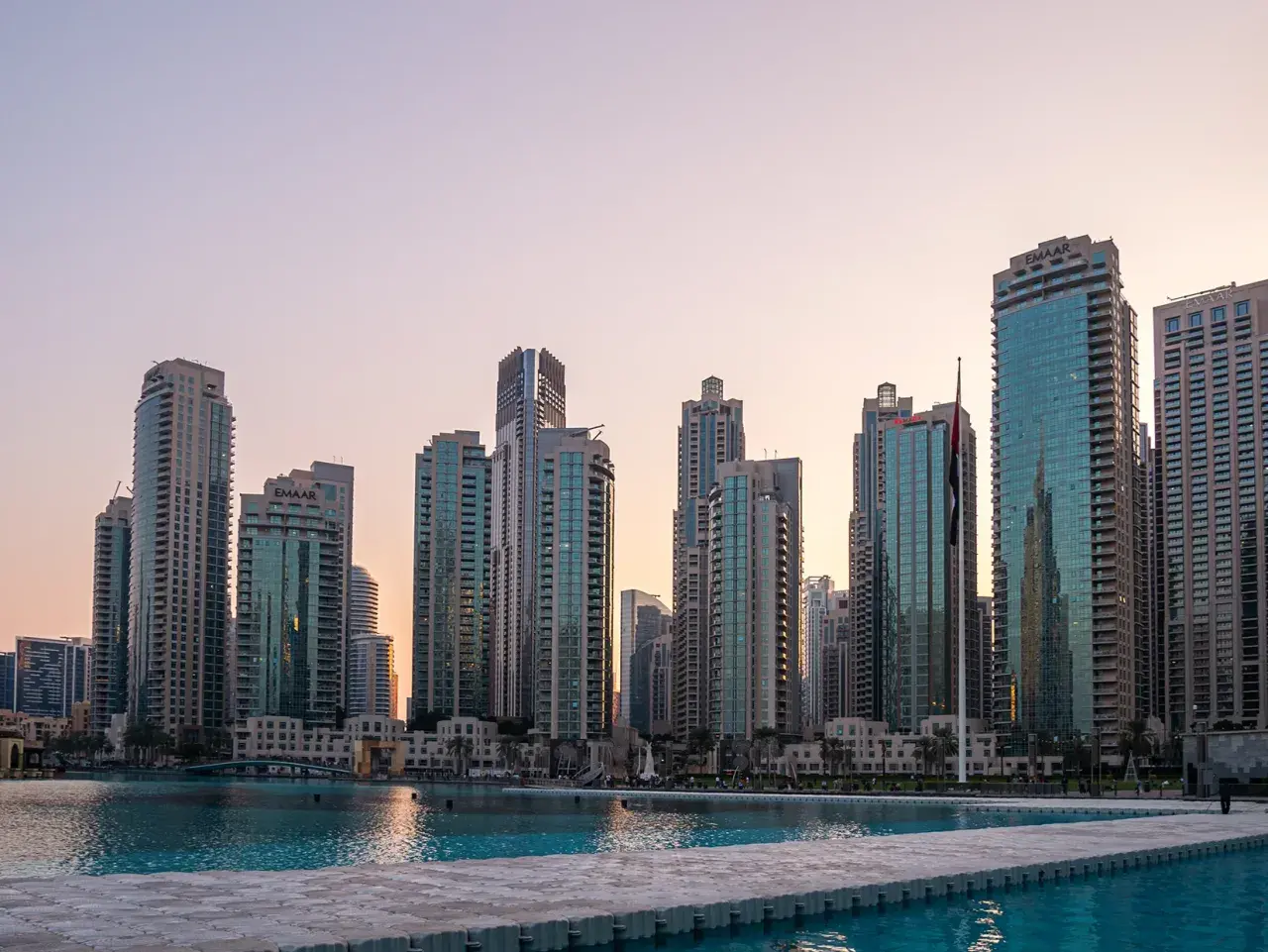Wieżowce w Dubaju o zachodzie słońca, w tym budynki Emaar. Wspaniałe dubaj atrakcje nad wodą.