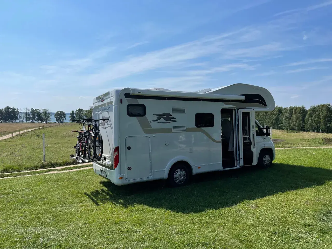 Kamper na trawie, gotowy na przygodę. Idealne miejsce na pola namiotowe Mazury, z widokiem na jezioro i las.