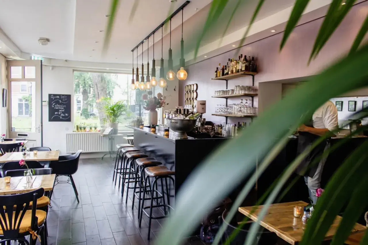 Wnętrze restauracji z barem, stołkami i stołami.