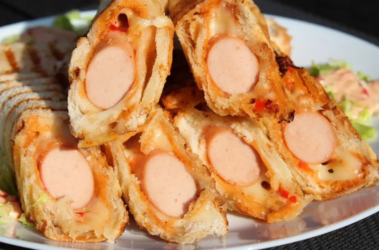 Pyszne domowe hot dogi w cieście, zapieczone z serem i papryką. Idealne na szybką przekąskę.