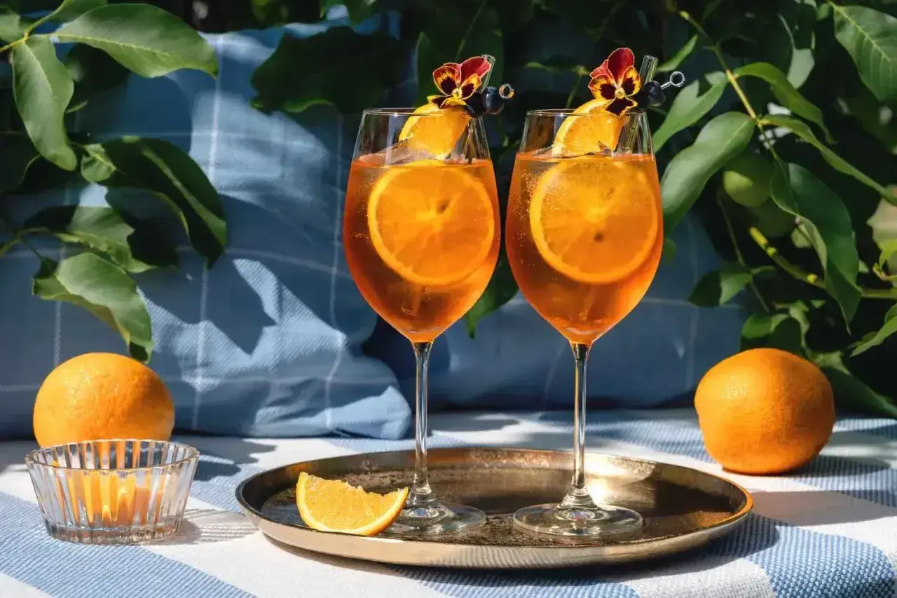 Dwa Aperol Spritz z pomarańczą i kwiatkiem. Idealne na lato, łatwo je zrobić!