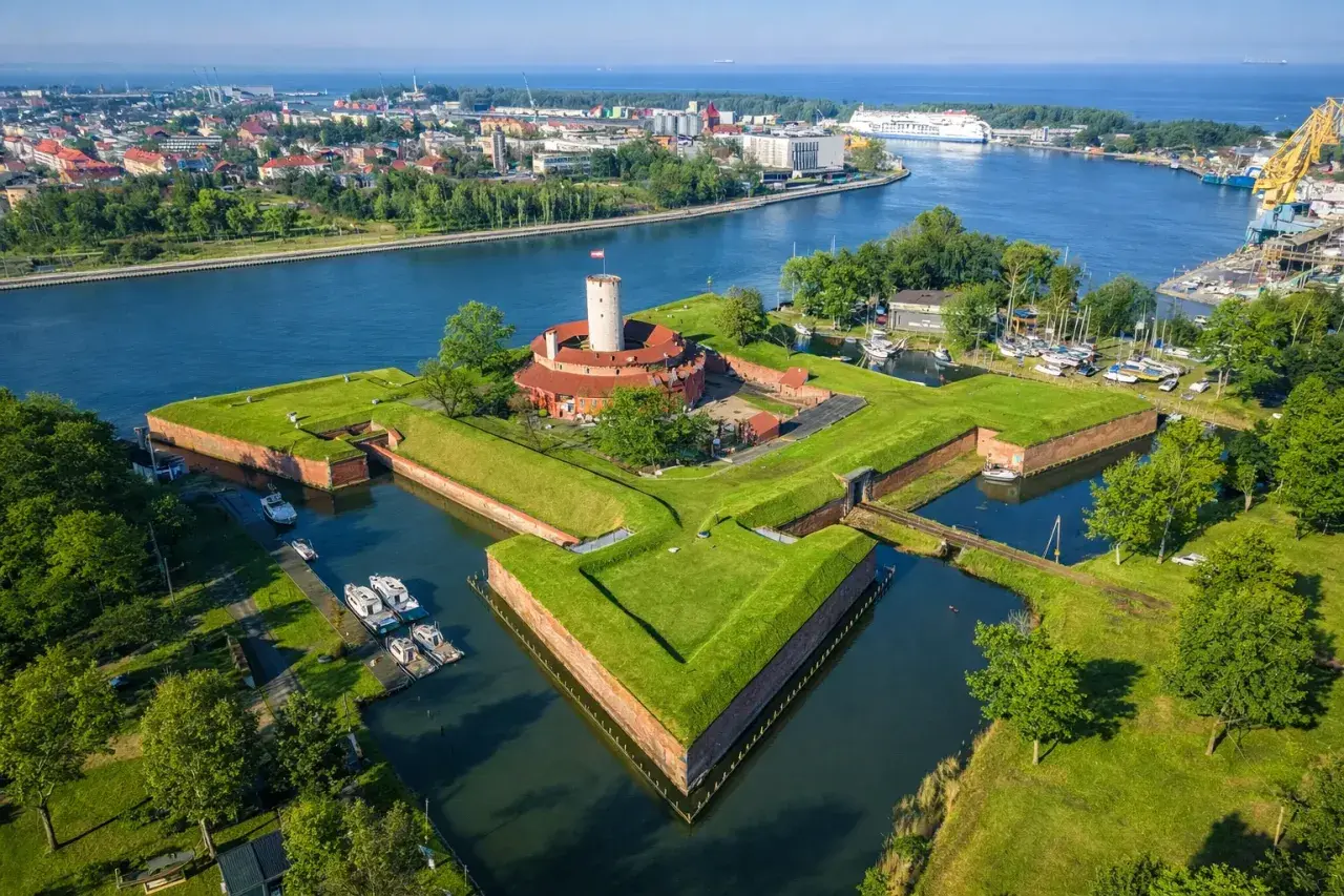 Twierdza Wisłoujście w Gdańsku – ciekawe miejsce do zwiedzenia, otoczone fosą i zielenią, z widokiem na port.